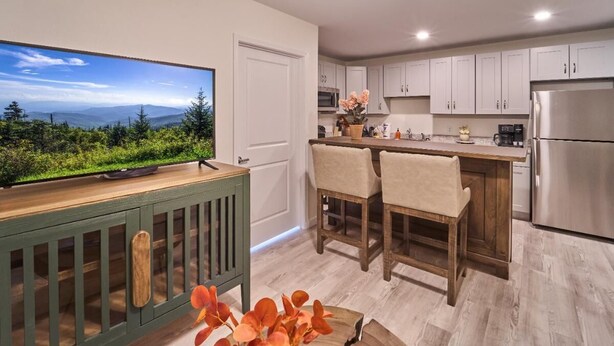 A kitchen with a large TV, wooden chairs, a wooden table, and a view of a mountainous landscape. - The Ruby 312 (Pigeon Forge)