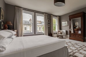 A bedroom with a large bed, a dresser, a chair, and a window with curtains. - Radipole Road IV - Three Bedroom House, Sleeps 6 (London)