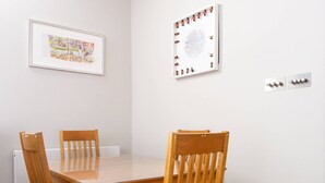 A dining table with four wooden chairs, white walls, a framed picture, and a whiteboard. - Red Lion Square - Two Bedroom Apartment, Sleeps 4 (London)