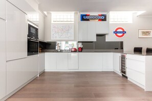 A modern kitchen with white cabinetry, a map on the wall, and a Red Lion Square sign. - Red Lion Square - Two Bedroom Apartment, Sleeps 4 (London)