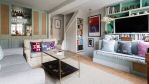 A living room with a sofa, a coffee table, a bookshelf, and a television. - Royal Crescent Mews - One Bedroom House, Sleeps 2 (London)