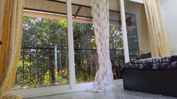 Ein Zimmer mit großem Fenster, einer schwarzen Couch und einem gemusterten Teppich.