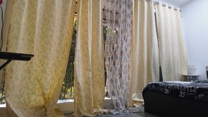 Ein Zimmer mit einem Bett, einem Vorhangfenster und einem kleinen Tisch.