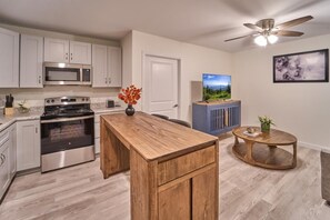 A modern kitchen with stainless steel appliances, a wooden island, and a ceiling fan. - The Ruby 313 (Pigeon Forge)