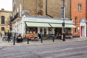 Ein Straßencafé mit Außenbereich, einer sichtbaren Schaufensterfront und einem Verbotsschild für Fahrräder.
