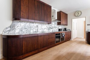 Eine Küche mit Marmorarbeitsplatte, Holzschränken und einer Uhr an der Wand.