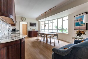 Eine moderne Küche mit Marmorarbeitsplatte, Holzschränken und einem Essbereich mit großem Tisch und Stühlen.