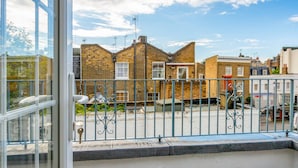A balcony with a view of a street, metal railing, and a building with brick walls. - Edge Street IV - Two Bedroom Apartment, Sleeps 3 (London)