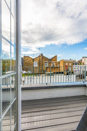 Ein Balkon mit Blick auf eine Straße, einem Metallgeländer und einem Gebäude mit Backsteinfassade.