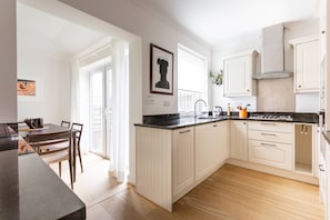 Eine moderne Küche mit weißen Schränken, einer schwarzen Arbeitsplatte und einem Essbereich mit Tisch und Stühlen.