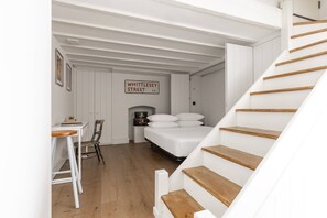 Ein Schlafzimmer mit Bett, Schreibtisch, Stuhl, einer Treppe und einem Schild an der Wand.