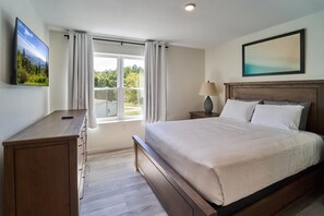A bedroom with a bed, a desk, a TV, a window with curtains, and a painting on the wall. - The Ruby 314 (Pigeon Forge)