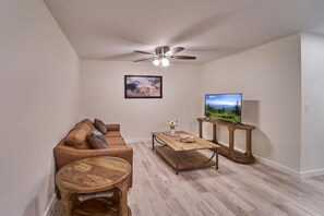 A living room with a sofa, coffee table, TV, and ceiling fan. - The Ruby 314 (Pigeon Forge)