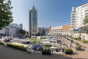 Ein Yachthafen mit vor Anker liegenden Booten, ein hohes Gebäude und eine Uferpromenade.