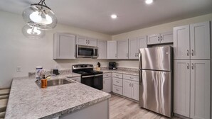 A modern kitchen with granite countertops, stainless steel appliances, and white cabinetry. - The Ruby 315 (Pigeon Forge)