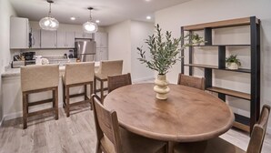 A modern kitchen with white cabinets, a round wooden table, and pendant lighting. - The Ruby 315 (Pigeon Forge)