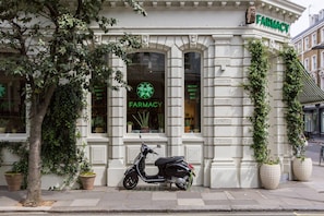 A building with a sign reading 'FARMACY' and a parked scooter in front. - Queens Gardens III - Two Bedroom Apartment, Sleeps 4 (London)