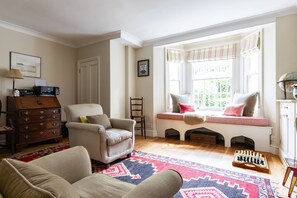 Ein gemütliches Wohnzimmer mit Kamin, einer Sitzbank mit Kissen, einem Schachbrett und einem Holzschrank.