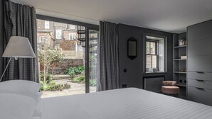 Ein Schlafzimmer mit einem großen Bett, einem Fenster, einem Sessel und einem Kleiderschrank.
