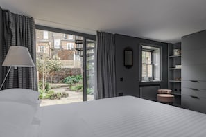 Ein Schlafzimmer mit einem großen Bett, einem Fenster, einem Sessel und einem Kleiderschrank.