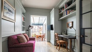 Ein gemütliches Zimmer mit einer Couch, einem Esstisch und einem Schreibtisch mit einem Computer.