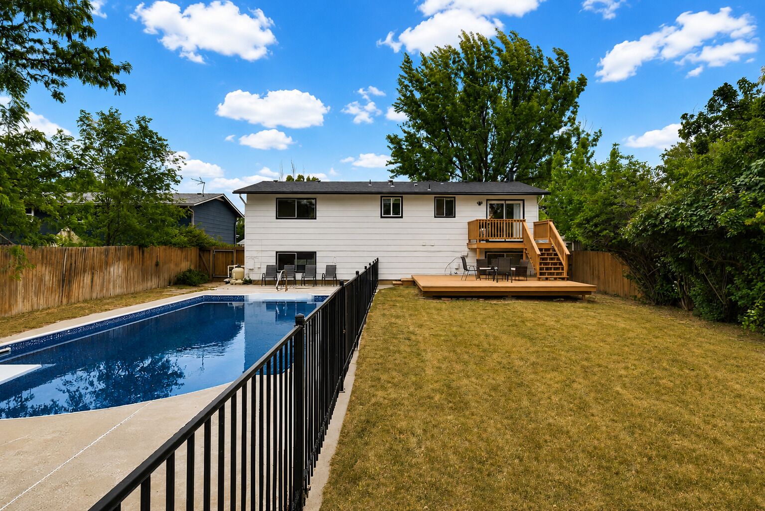 A two-story house with a swimming pool, a deck, and a fenced yard.