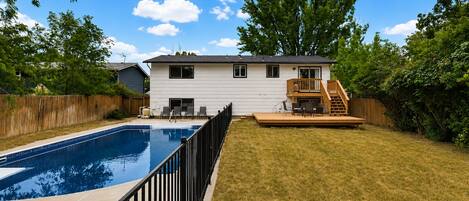 A two-story house with a swimming pool, a deck, and a fenced yard.