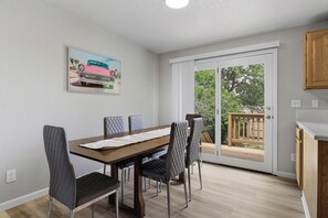 Ein Essbereich mit Tisch und Stühlen, einem Gemälde an der Wand und einer Glastür zu einer Terrrasse.