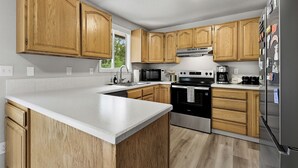 A modern kitchen with wooden cabinets, stainless steel appliances, and a white countertop. - Rad Pad - Arcades, Seasonal Pool (Boise)