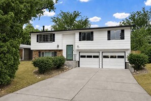A two-story house with a garage, a brick section on the ground floor, and a green door. - Rad Pad - Arcades, Seasonal Pool (Boise)
