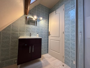 A bathroom with a dark cabinet, a white door, and a tiled wall. - House near the landing beaches Sainte Mere Eglise/Carentan (Boutteville)