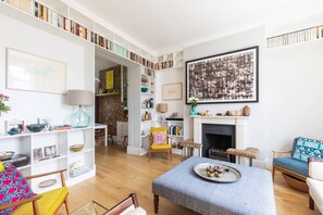 Ein Wohnzimmer mit Kamin, Bücherregalen, einem Couchtisch und einer Couch.