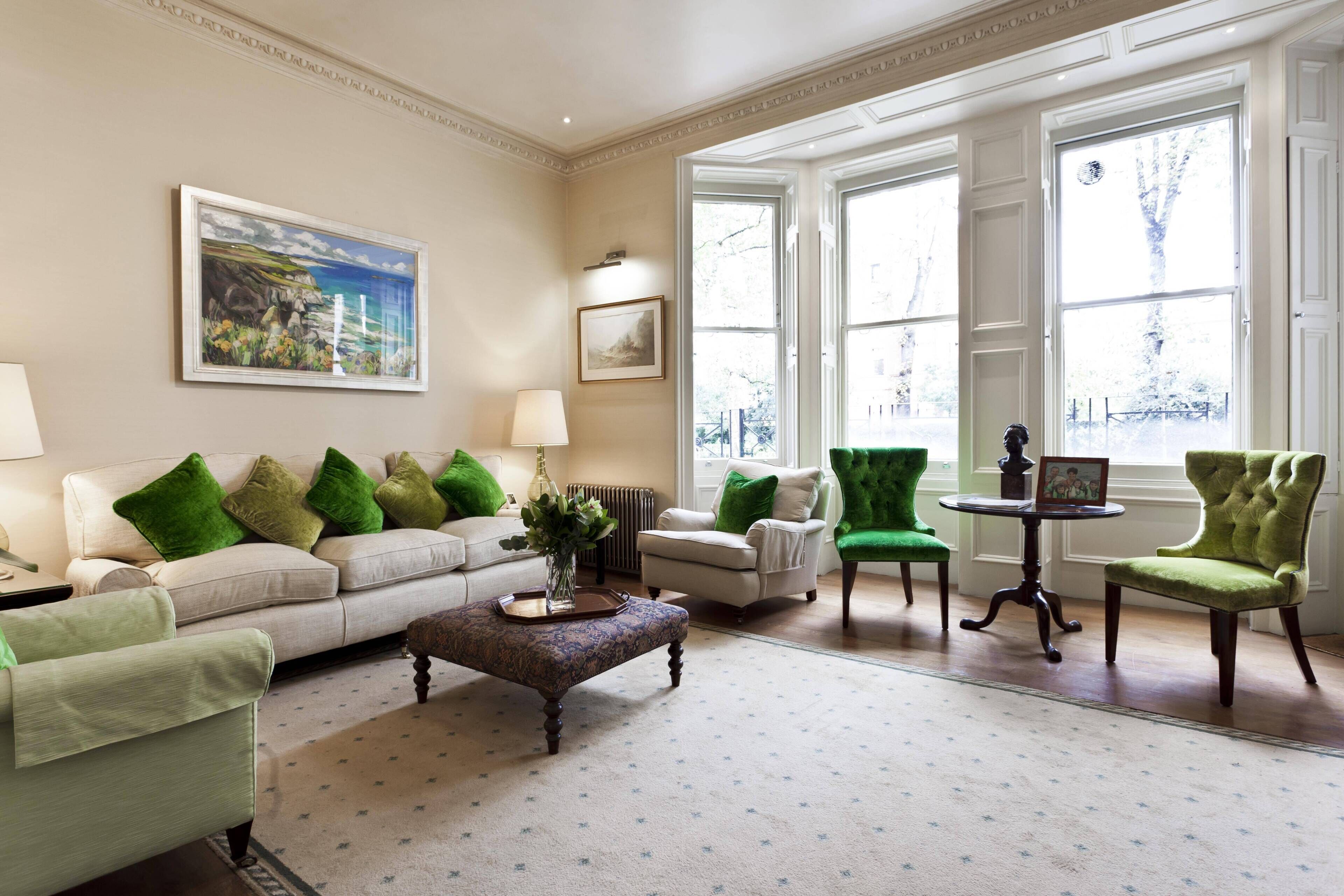 A living room with a sofa, armchairs, a coffee table, and a painting on the wall.
