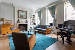 Ein Wohnzimmer mit Klavier, Sofa, Couchtisch und Kamin.