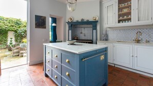 Een keuken met een blauw kookeiland, witte kasten en een betegelde spatwand.