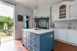 Eine Küche mit einer blauen Kochinsel, weißen Schränken und einer gefliesten Spritzschutzwand.