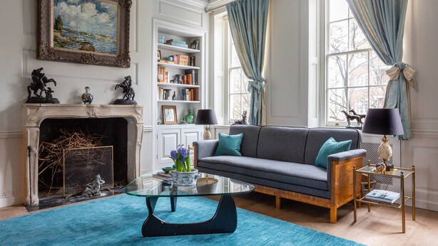 Een woonkamer met een open haard, een bank, een glazen salontafel en een boekenkast.