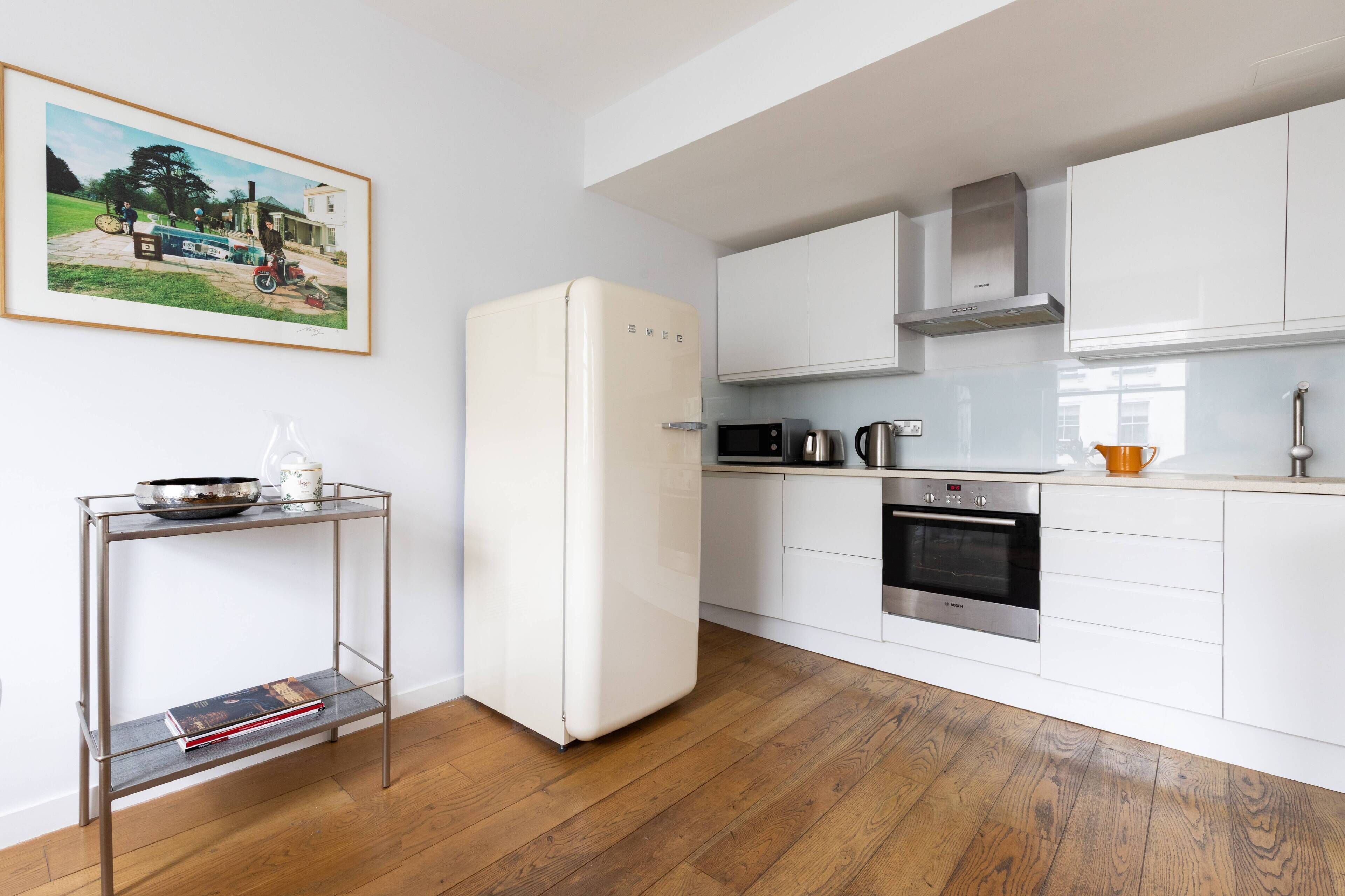 A modern kitchen with white cabinetry, a stainless steel oven, and a white refrigerator.