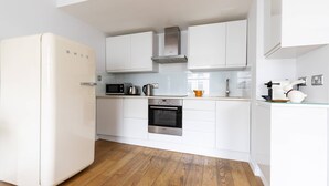 A kitchen with white cabinets, a stainless steel oven, a microwave, and a refrigerator. - St Stephen's Gardens VIII (London)