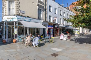 A street with outdoor seating, a cafe, and a bar. - St Stephen's Gardens VIII (London)