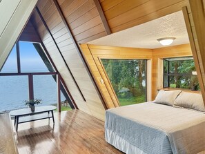 A bedroom with a large bed, a view of the sea, and a table with a plant. - 2 Homes Waterfront Lakeview Estate Sleeps 12 Private Beach Olympic National Park (Amanda Park)
