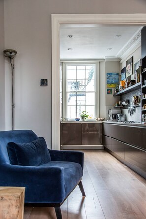 Eine moderne Küche mit Einbauofen, einem Fenster mit Blick auf die Stadt und einem blauen Sofa im Wohnbereich.