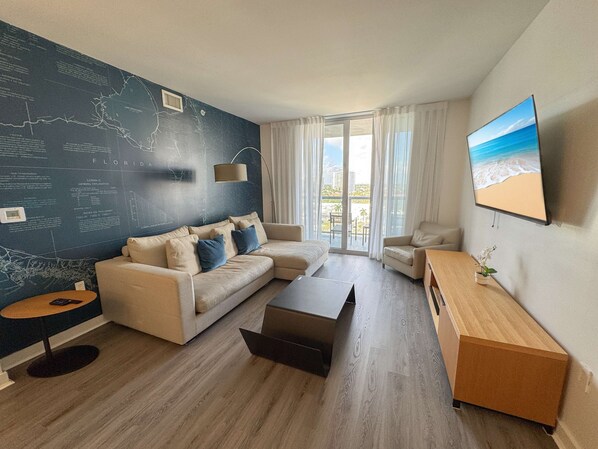 Un salon moderne avec un canapé d’angle, une table basse et un téléviseur fixé au mur.