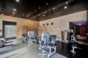 Ein Fitnessraum mit Trainingsgeräten, Holzwänden und einer Spiegelwand.