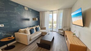 A modern living room with a sectional sofa, a coffee table, and a TV on the wall. - Elegant 1BR, Marina View, Pool & Beach Shuttle (Hallandale Beach)