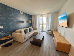 Ein modernes Wohnzimmer mit einem Ecksofa, einem Couchtisch und einem Fernseher an der Wand.