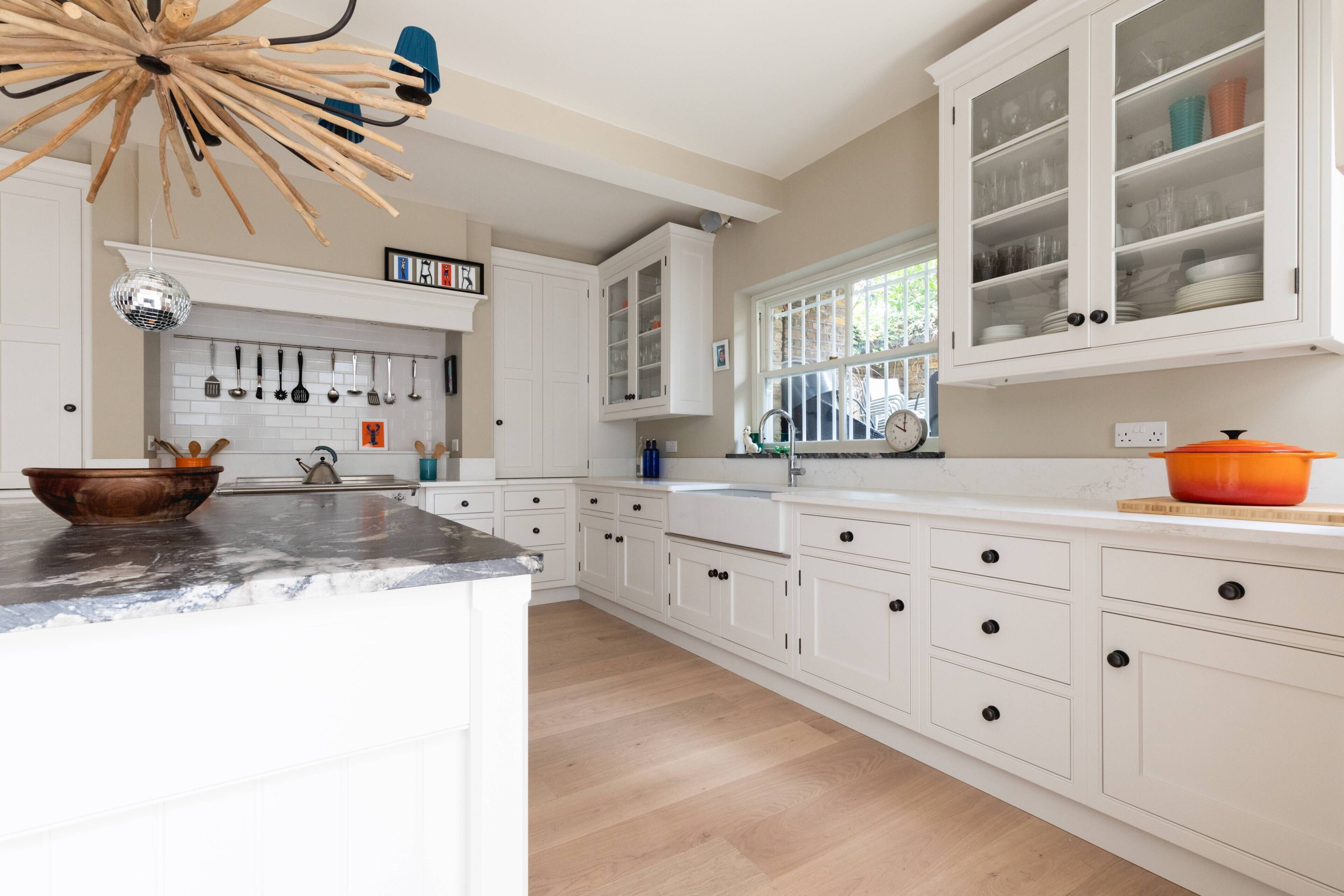 Una cocina con armarios blancos, un tazón de madera sobre la encimera y una bola de discoteca.