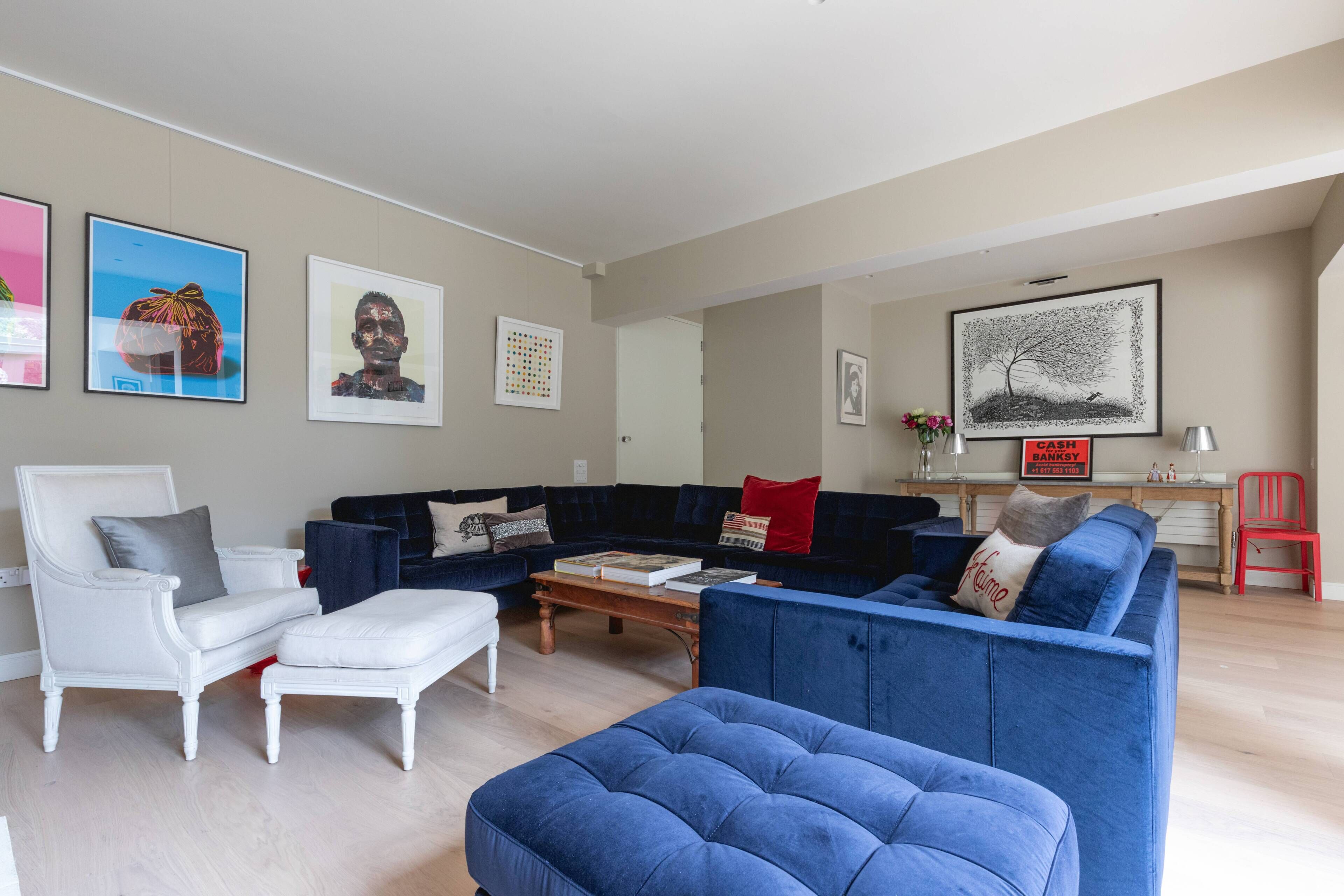 Un salon avec un fauteuil blanc, un canapé bleu et une table basse.