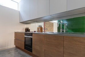 Eine moderne Küche mit Holzausstattung, einem eingebauten Ofen und einer grünen Spritzschutzwand.