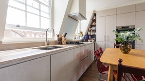 Eine moderne Küche mit einem großen Fenster, einem eingebauten Herd und einem Essbereich mit einem Holztisch und Stühlen.